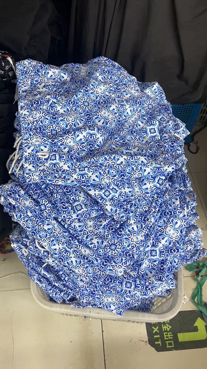 Bulk blue and white tile print swim shorts stacked after production